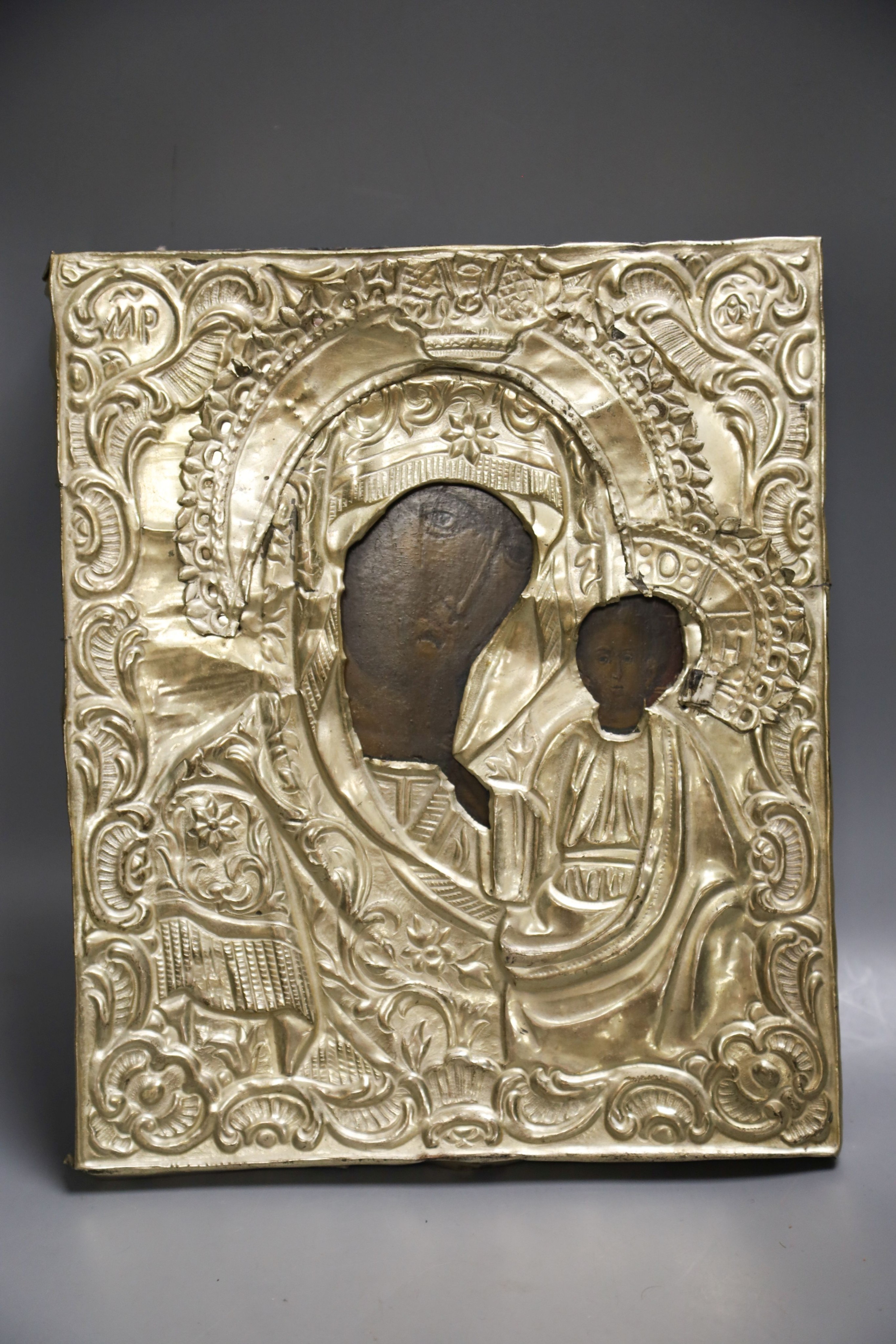 A Russian base metal oklad icon and a similar enamelled bronze panel, once part of a tryptich 27x23cm